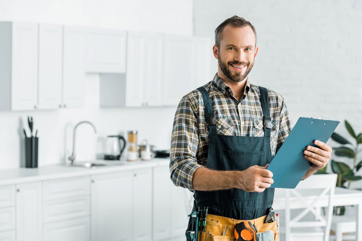 Plumber holding notebook in Perth kitchen.